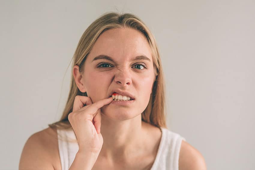 young woman picking at her red, swollen gums