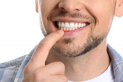 closeup of a man's smile pointing to his red, swollen gums